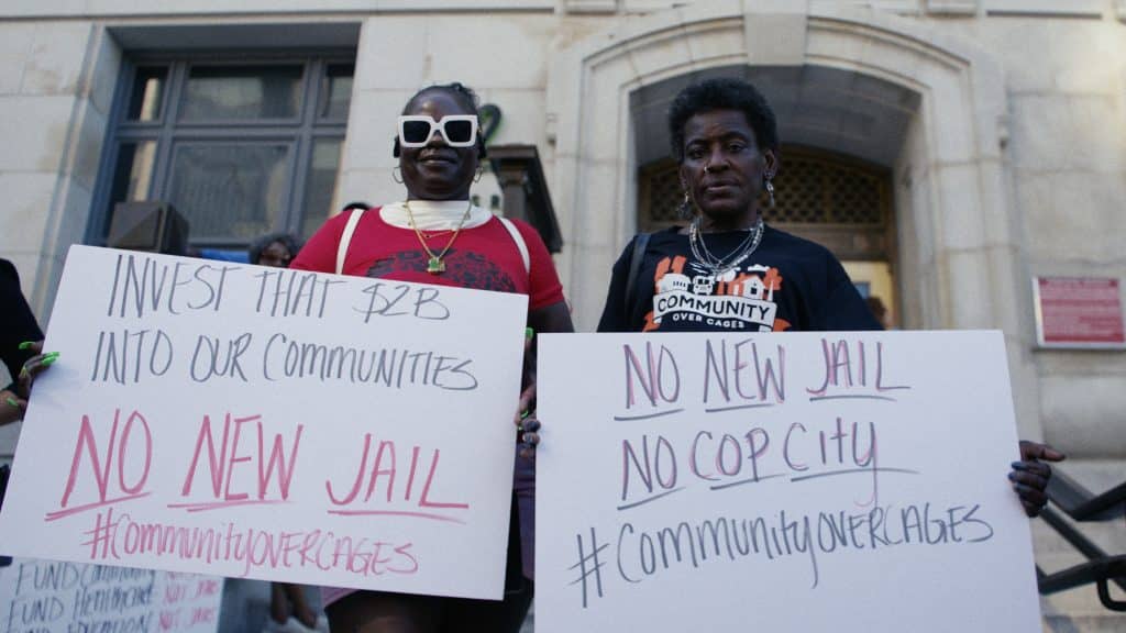 Two advocates stand outside the Fulton County Courthouse holding signs protesting a proposed $2B jail in Fulton County. The measure was defeated, prompting efforts by the county to purchase the Atlanta City Detention Center.