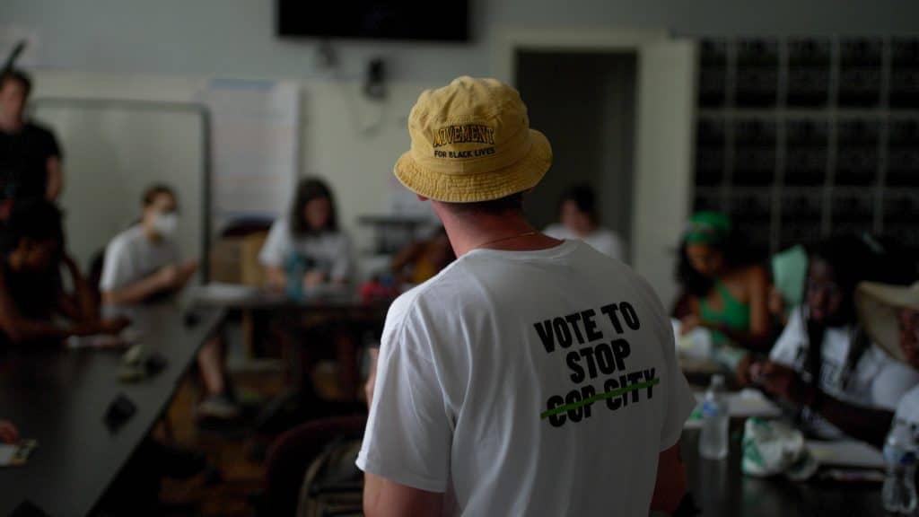 An organizer from the Cop City Vote campaign stands around a table of petition gatherers.