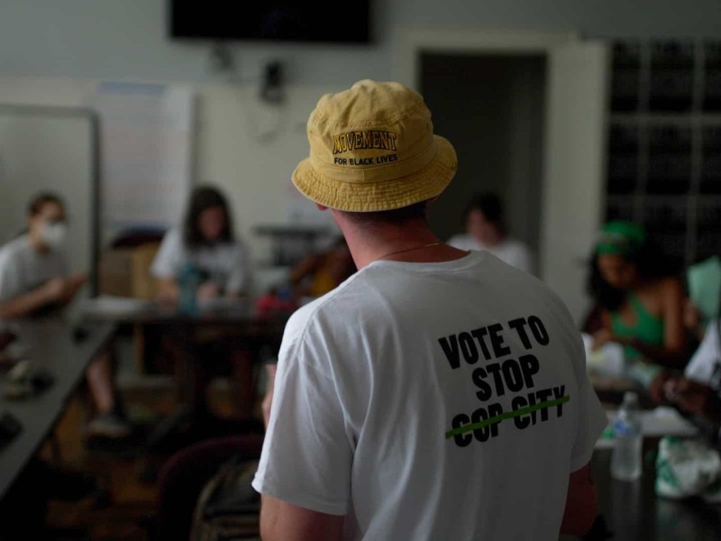 An organizer from the Cop City Vote campaign stands around a table of petition gatherers.