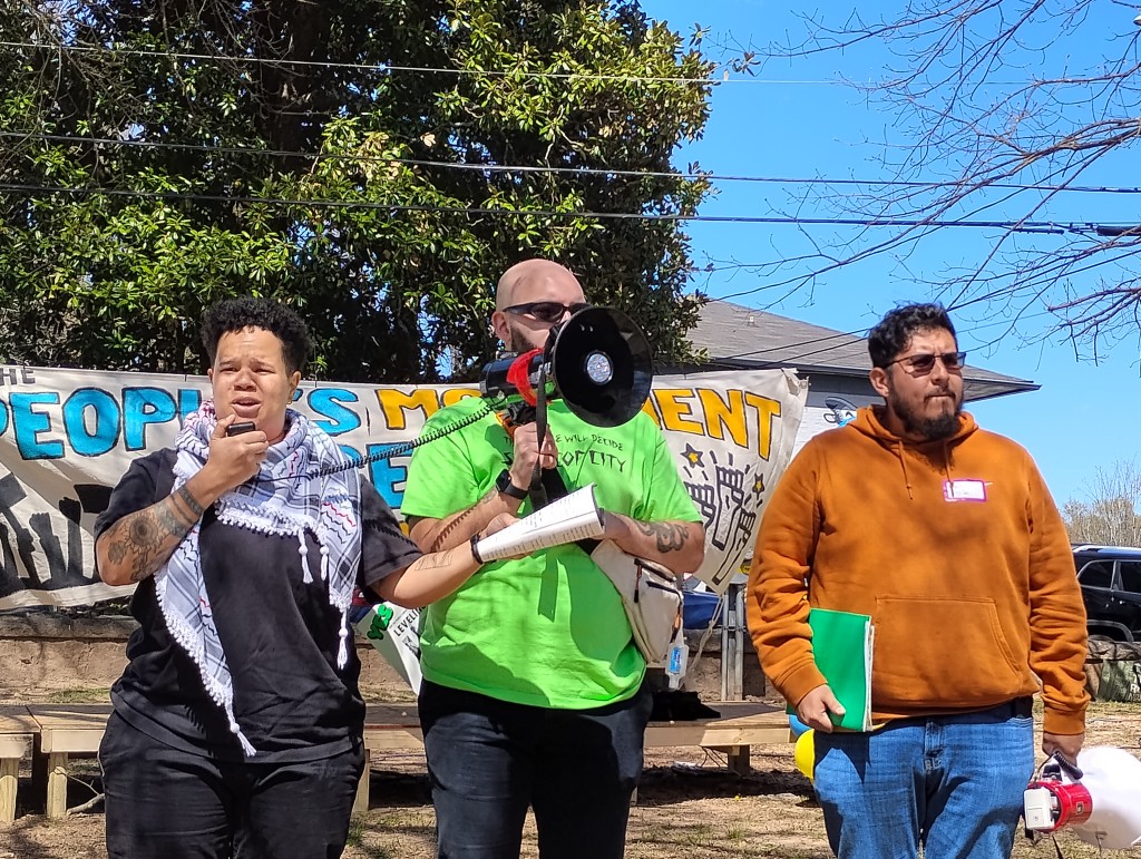 Three organizers stand on stage at the People's Movement Assembly in Atlanta to redefine public safety.