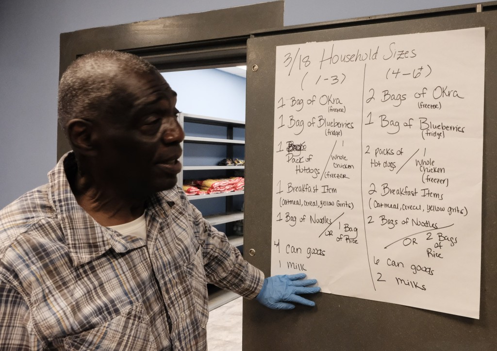 Stroble, a participant and worker at PAD's Care Navigation facility, explains how food items are distributed, which is based on household sizes.
