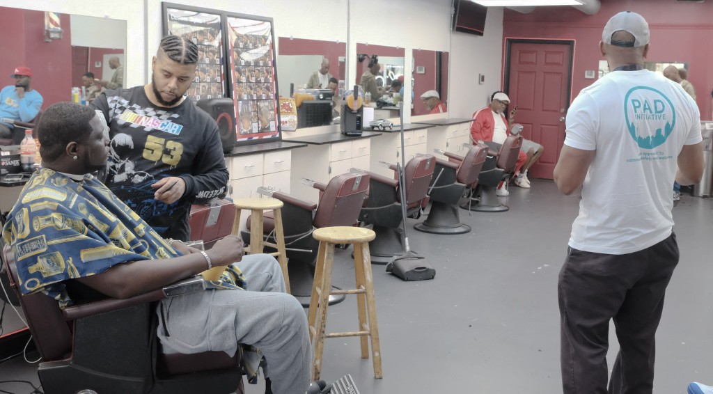 Commumity Response Team member Christian visits a barber shop to spread awareness about PAD's work.