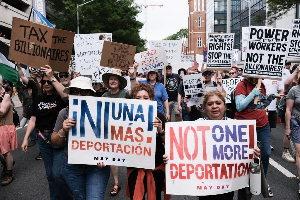 Marchers hold anti-deportation signs during the "Stop the Billionaire Agenda" march on International Workers Day in Downtown Atlanta.